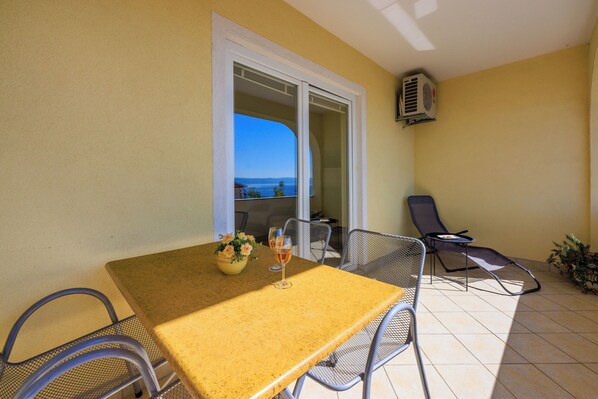 A balcony with a table, chairs, and a view of the sea. - Apartments Petak (Dramalj)