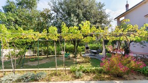 Ein Garten mit einer Pergola, Schaukeln und einem kleinen Spielbereich.