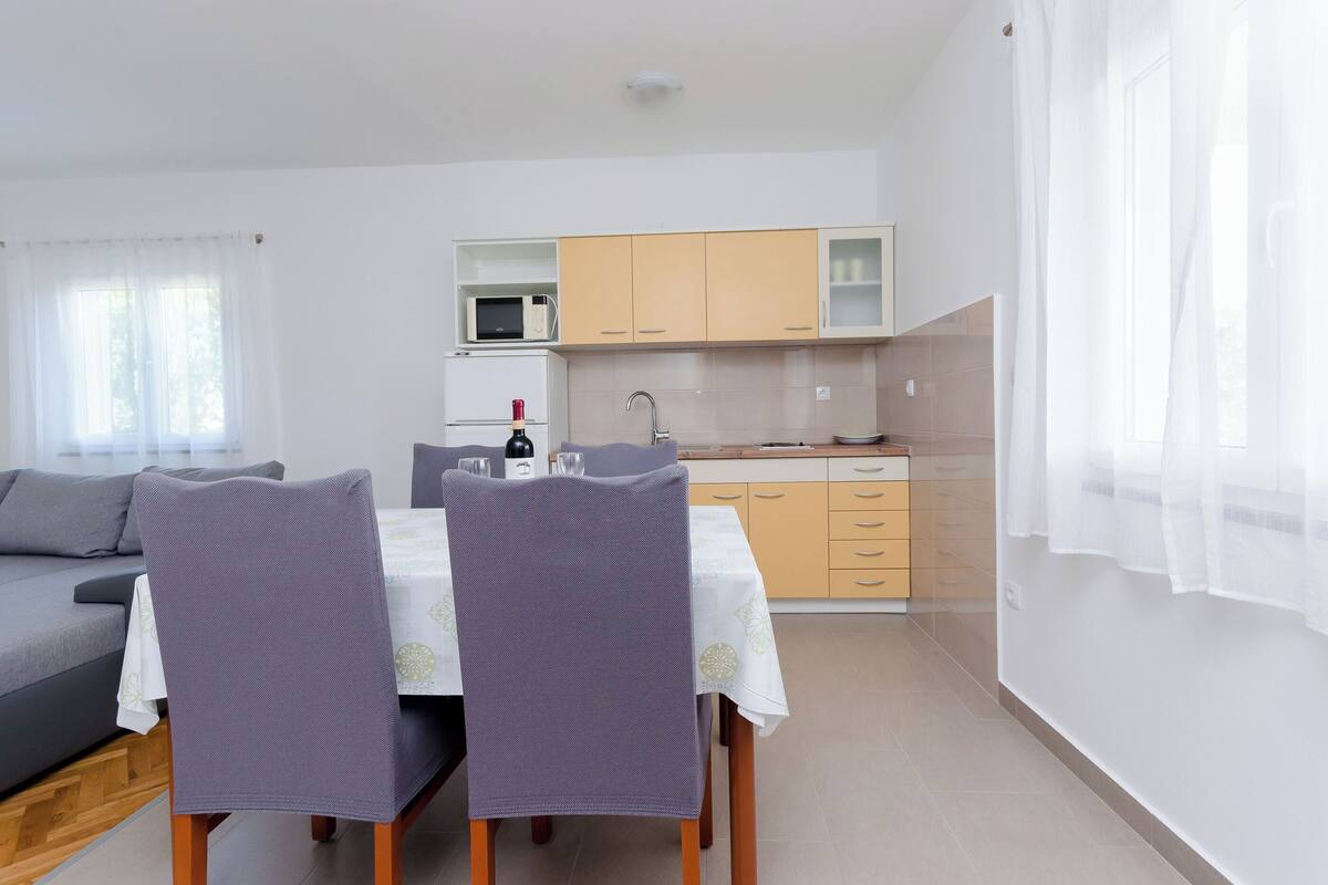 A modern kitchen with a dining area, featuring a microwave, cabinets, and a sink.