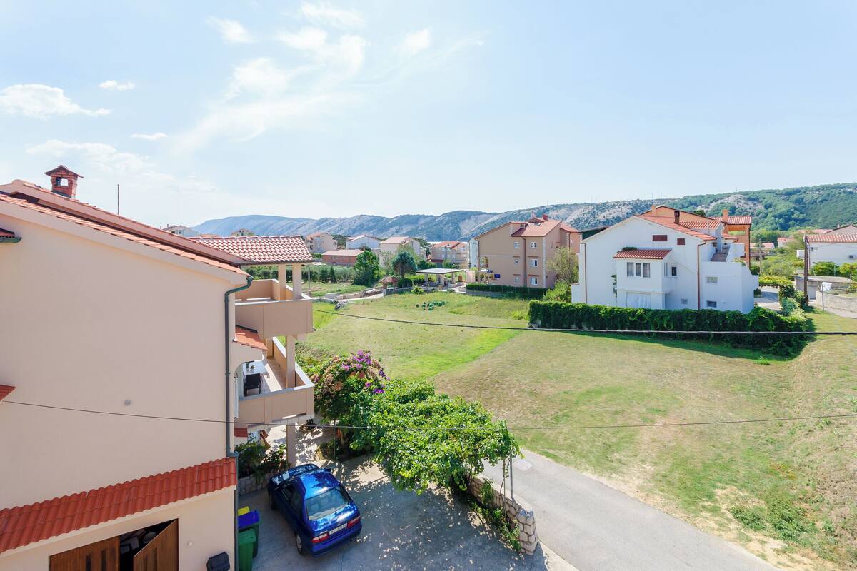 A residential area with houses, a blue car, and a clear sky.