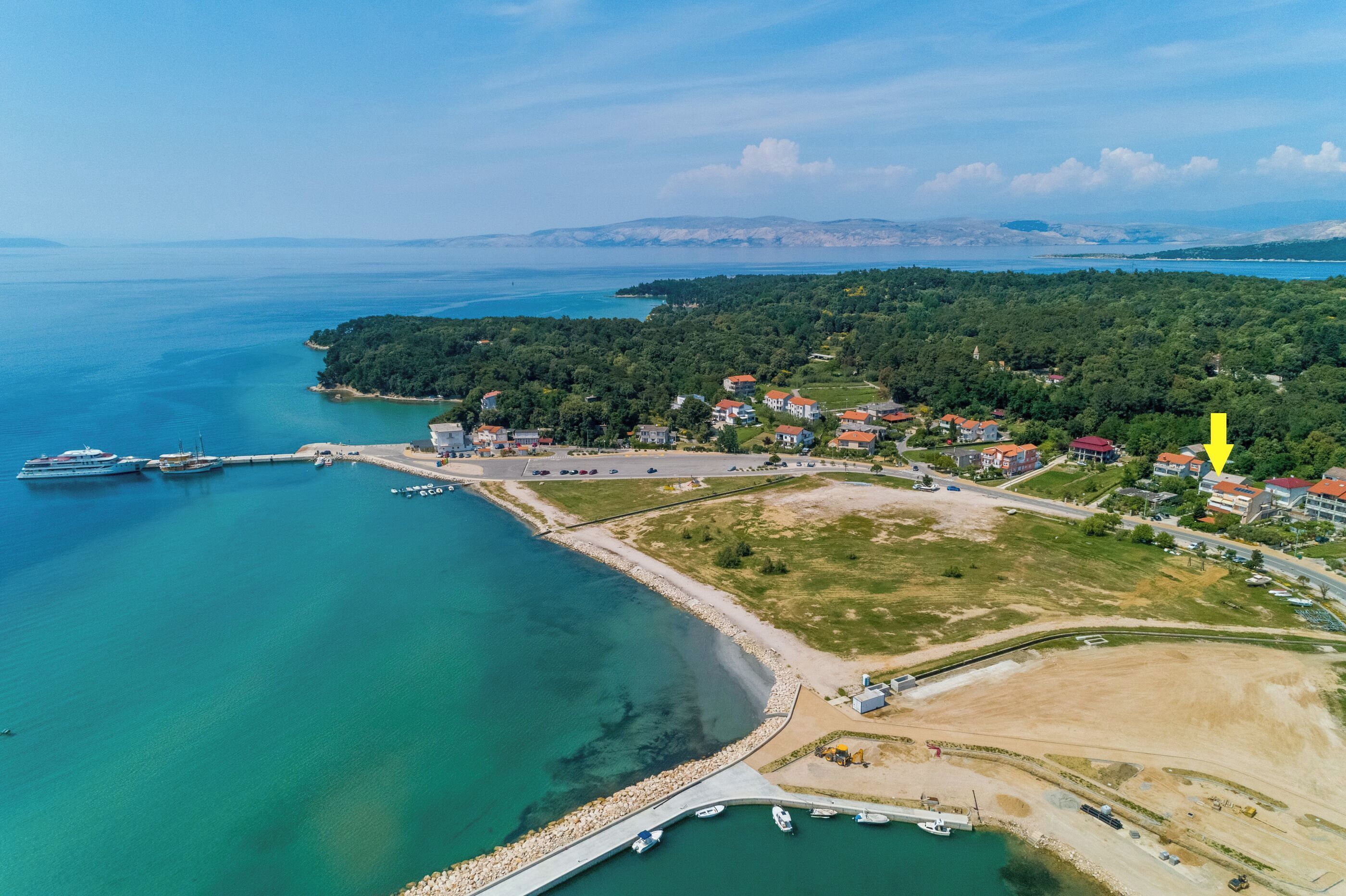 An aerial view of a coastal town with a marina, houses, and a bridge.