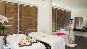 Experience tranquility in our serene spa room, featuring two treatment tables, a large mirror, and a sink.