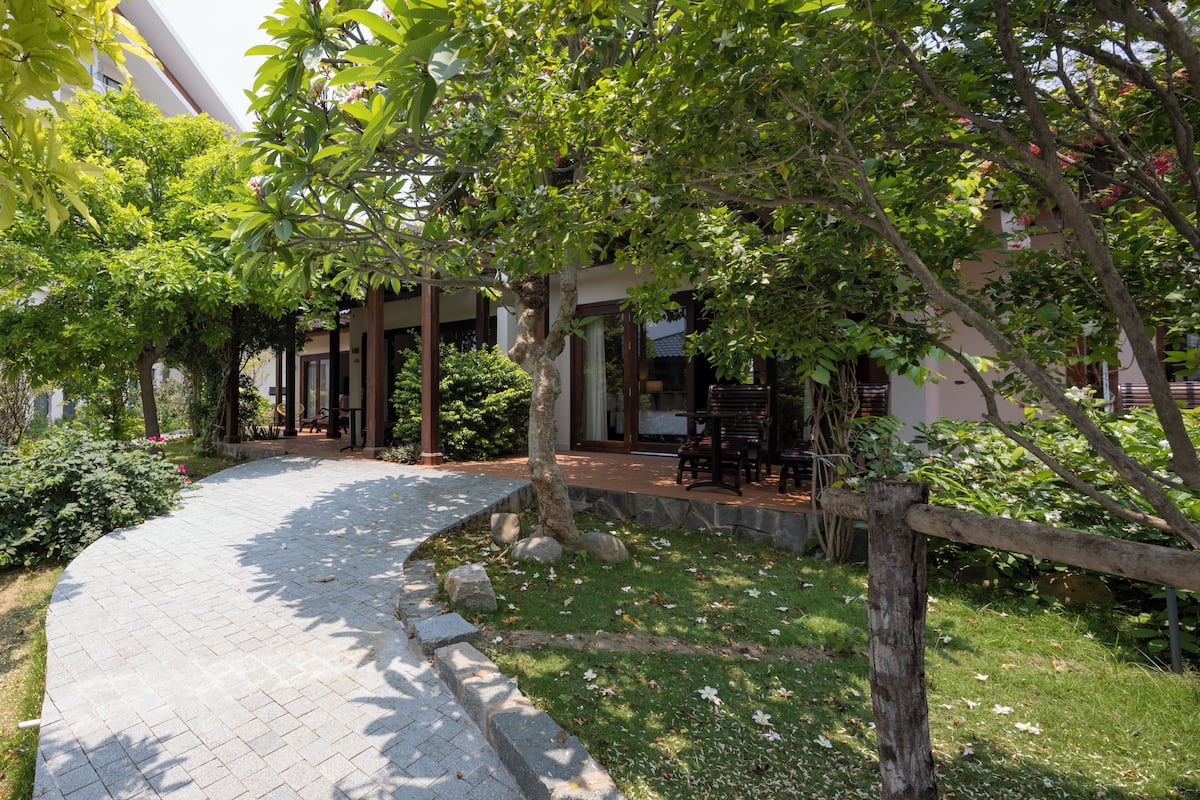 A paved pathway leading to a building with outdoor seating.