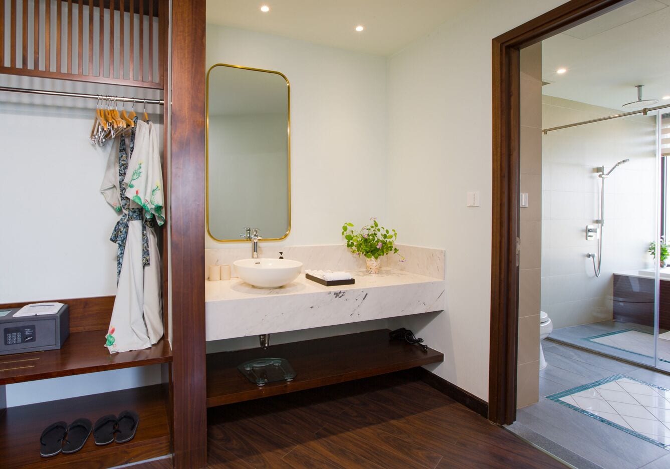 Une salle de bain moderne avec un meuble-lavabo en bois, un grand miroir, un lavabo blanc et une cabine de douche en verre.