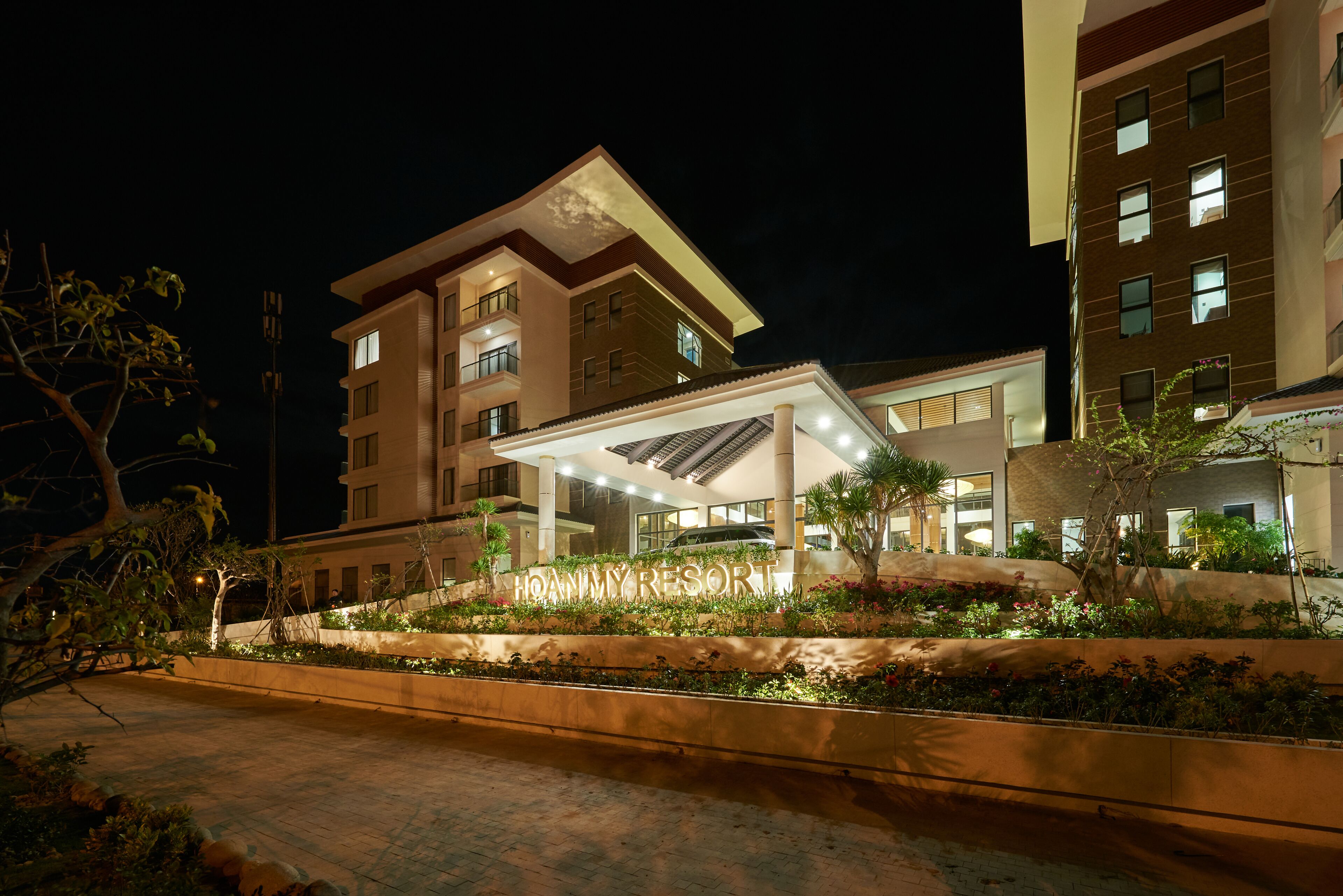 A hotel with a covered entrance, multiple floors, and a landscaped garden area.