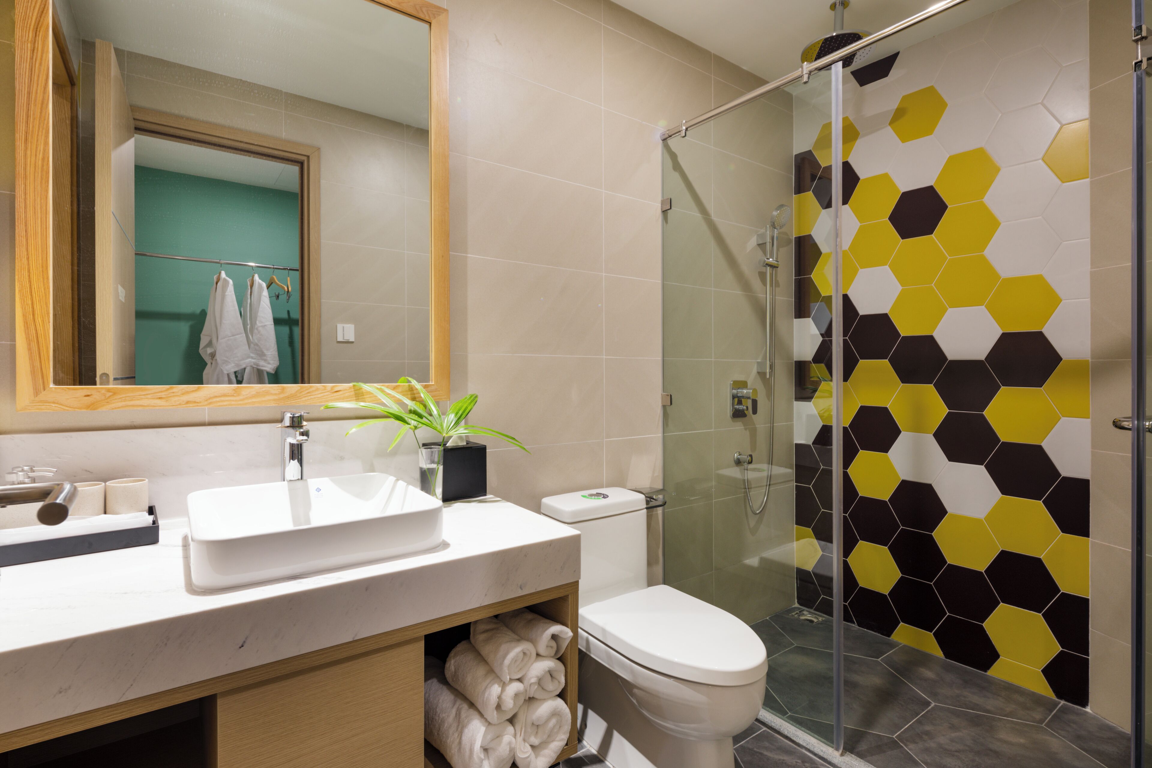 Un baño moderno con cabina de ducha de vidrio, un lavabo blanco y un inodoro.