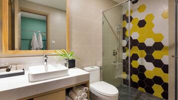 Un baño moderno con cabina de ducha de vidrio, un lavabo blanco y un inodoro.