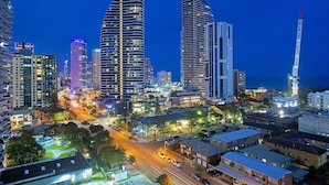 A cityscape at night with modern high-rise buildings, a prominent tower, and a well-lit street. - Savannah Penthouse (Broadbeach)