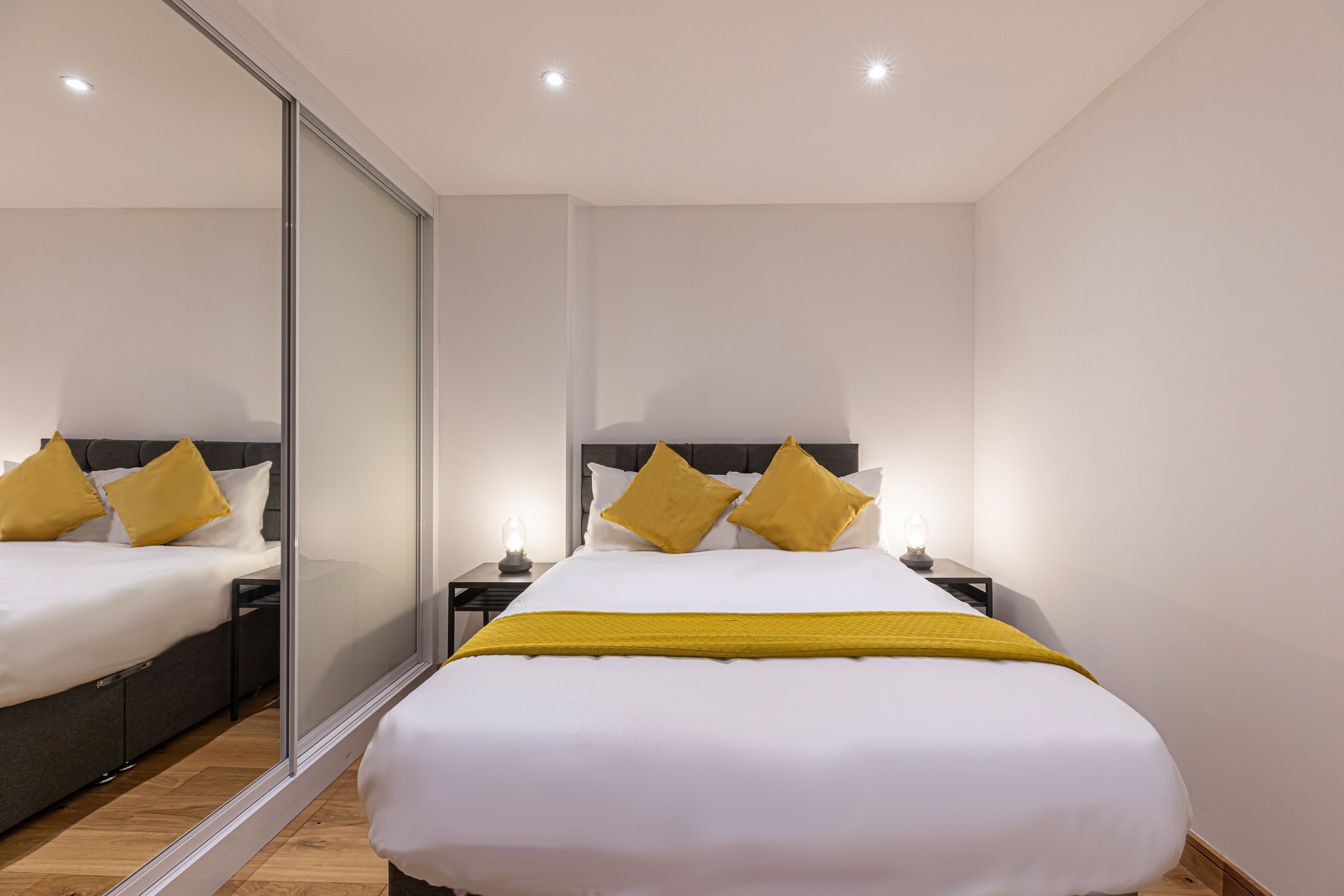 Una habitación de hotel moderna con una cama grande, una mesita de noche y un espejo.