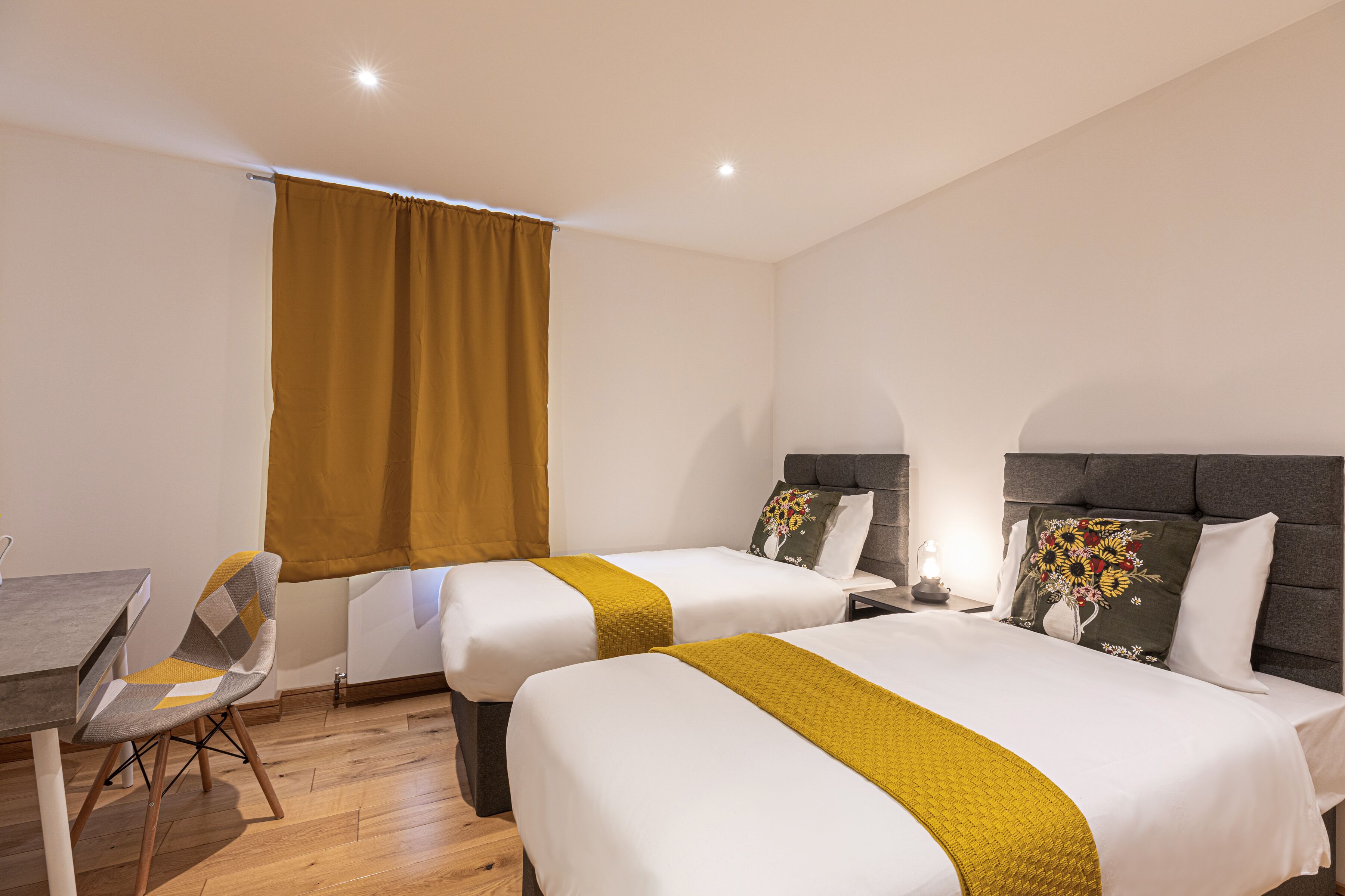 A hotel room with two beds, a dining table, and a chair.