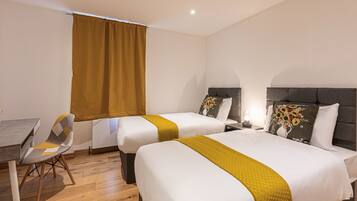 A hotel room with two beds, a dining table, and a chair.