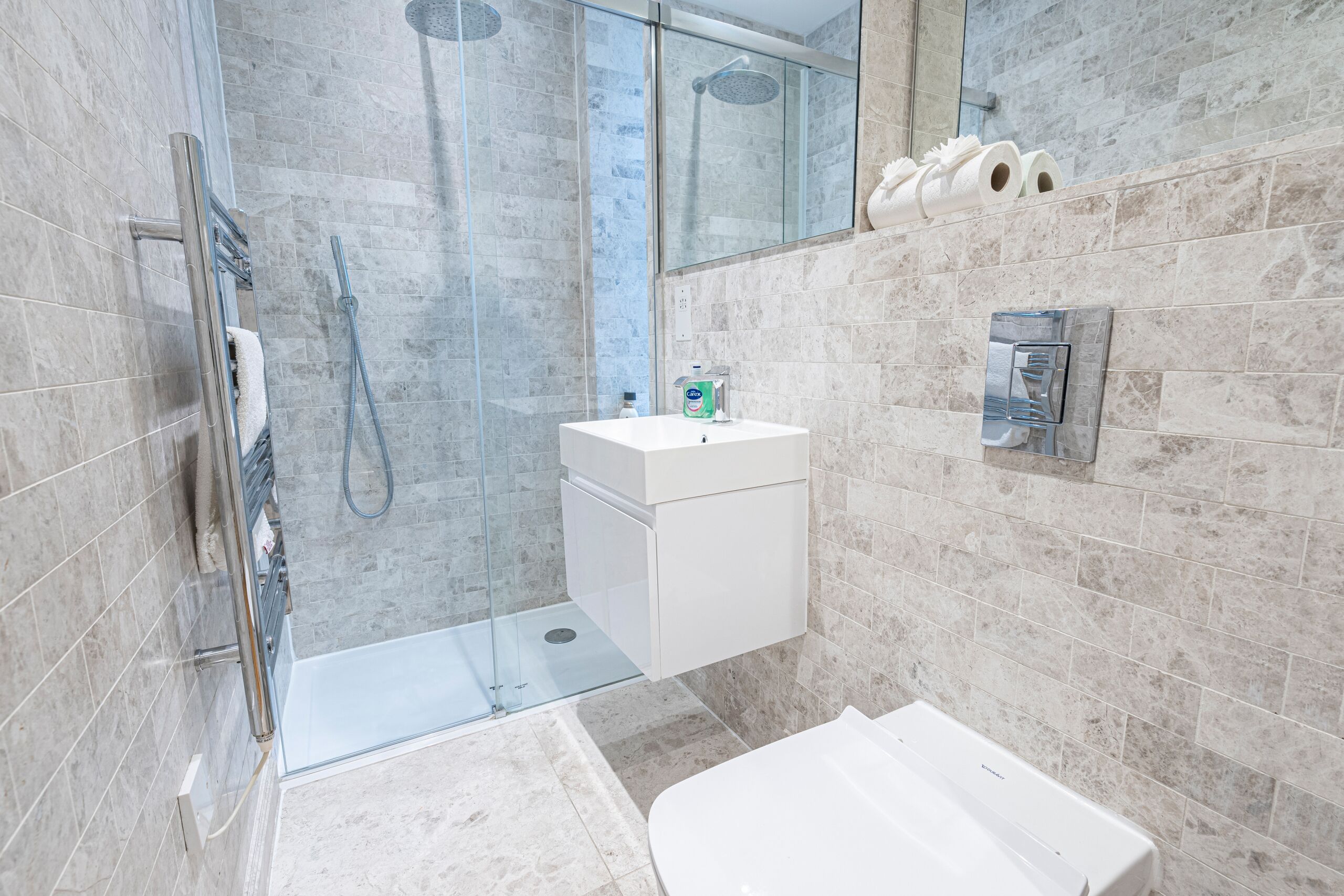 A modern bathroom with a glass-enclosed shower, a white sink, and a toilet.