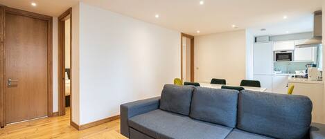 A modern living room with a grey sectional sofa, wooden flooring, and a small wooden coffee table.