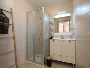 A bathroom with a glass-enclosed shower, a white vanity with a mirror, and a wooden ladder against the wall. - Cosy 2-Room Apartment in Briançon, Terrace, 4 Guests, WiFi, Parking, 3-Star Rating (Briançon)