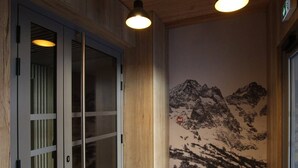 A hallway with wooden paneling, a glass door with a frosted panel, and a wall mural of a mountain landscape.