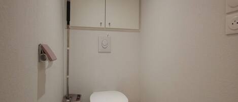 A small, clean bathroom with a toilet, a trash bin, and a towel rack.
