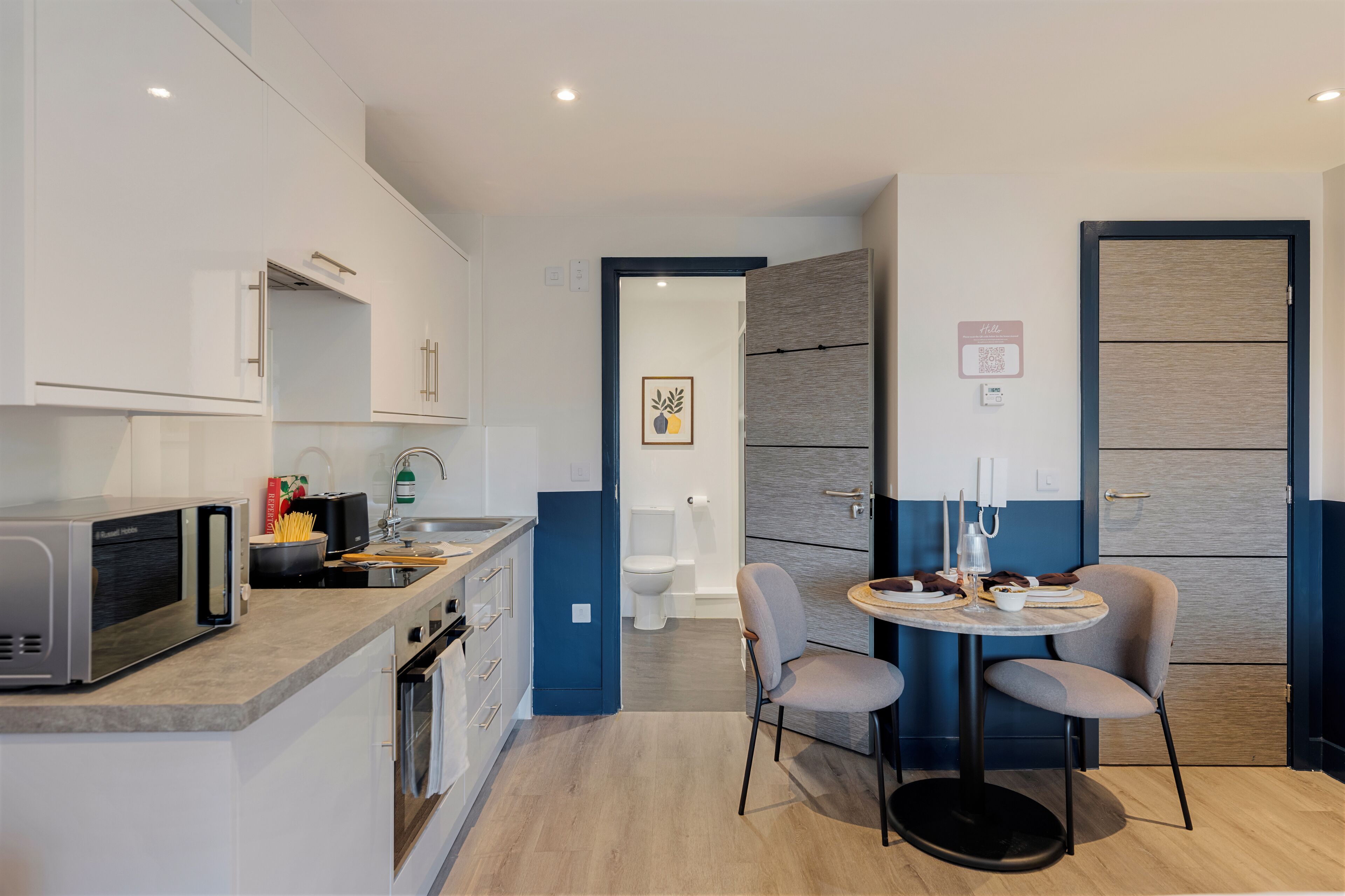 Cocina moderna con microondas, estufa y lavaplatos.  Hay un comedor con mesa y sillas.