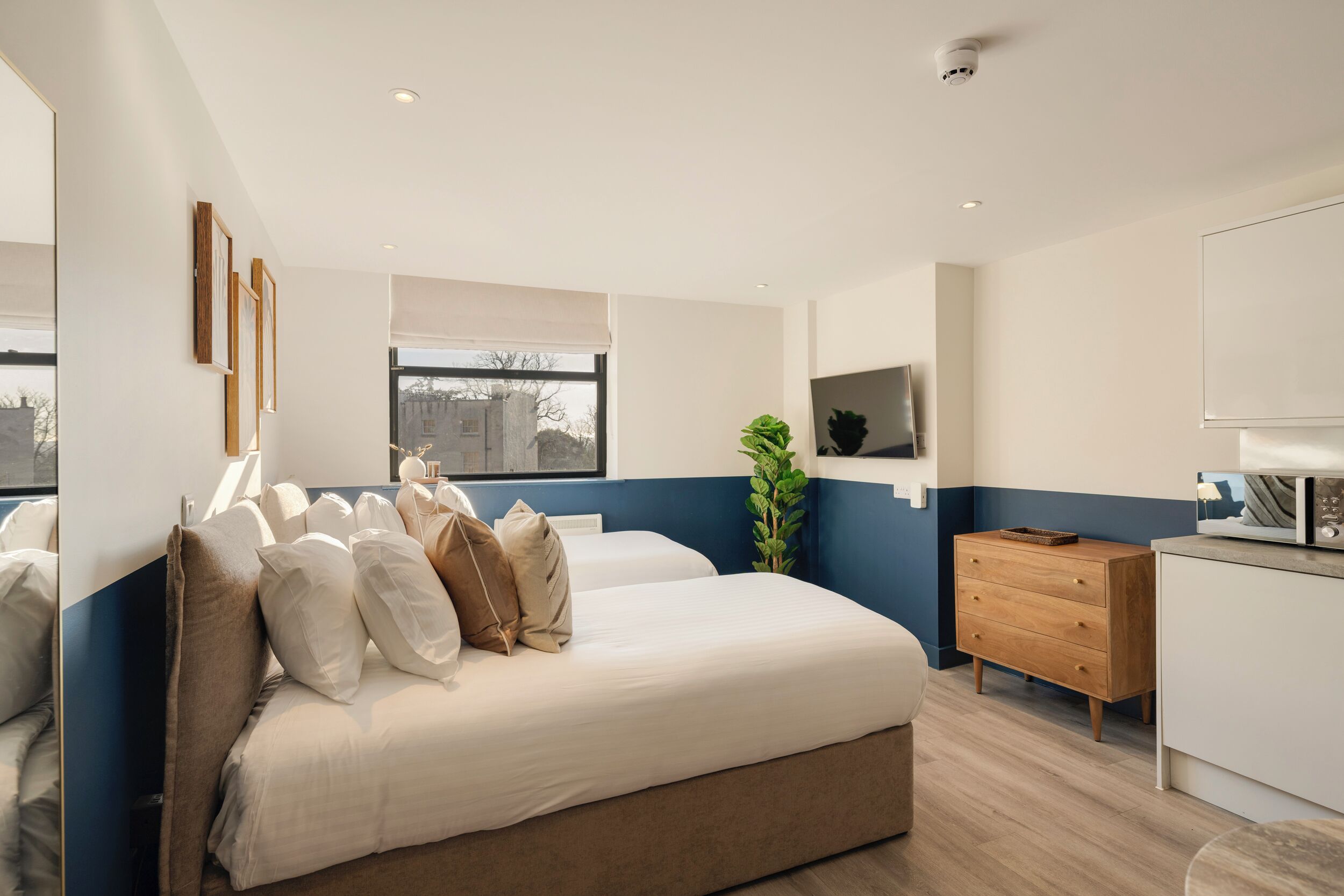 Un dormitorio moderno con una cama grande, un aparador de madera y una ventana con vistas a edificios.