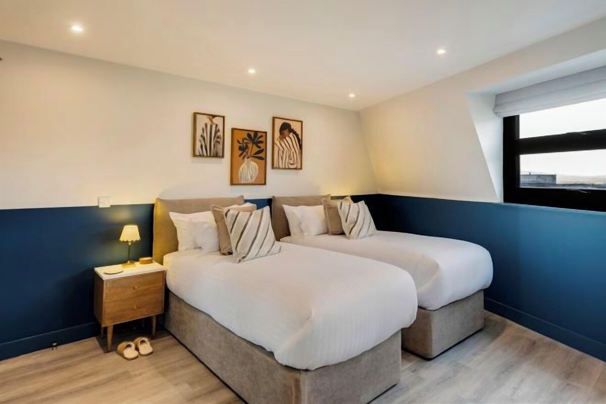 Une chambre avec deux lits, une table de chevet et une fenêtre.
