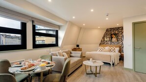 Une chambre d’hôtel moderne dotée d’un coin repas, d’un lit et offrant une vue sur le paysage urbain.