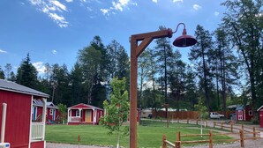 A red building with a porch, a wooden fence, and a gravel path. - Cabin #5 | 10 Min to Glacier Park Entrance, Minutes to Glacier Park! (Coram)