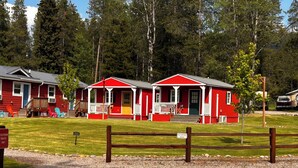 Eine rote Holzhütte mit Veranda und einem Schotterweg.