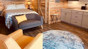 Une chambre moderne comprenant un lit, un canapé, une petite table et un coin cuisine avec des placards et un four à micro-ondes.
