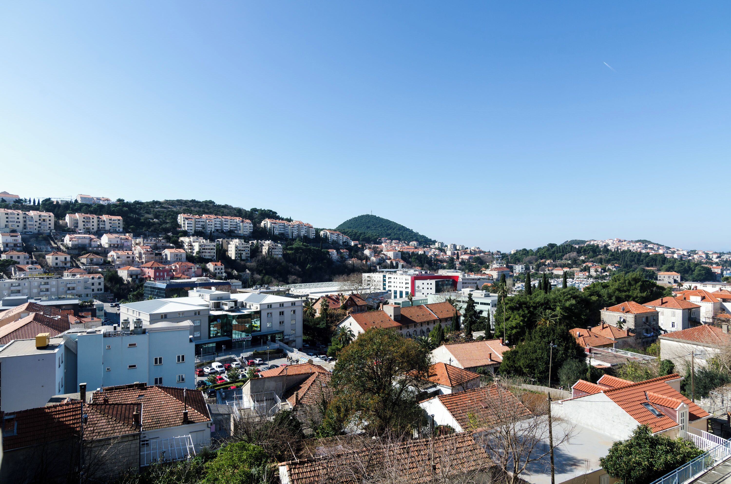 Paisagem costeira com edifícios residenciais e uma colina imponente ao fundo.