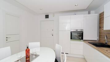 Una cocina moderna con armarios blancos, horno integrado y una pared decorativa de madera.