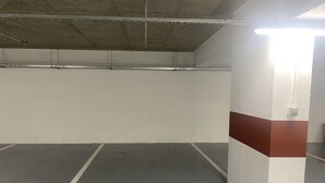 Un estacionamiento vacío con paredes de hormigón, una franja blanca y roja en una pared, y el número 79 pintado en el suelo.