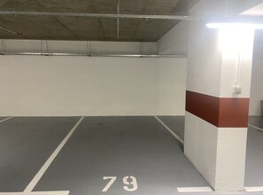 An empty parking garage with concrete walls, a white and red stripe on one wall, and the number 79 painted on the floor. - Apartment Iva (Dubrovnik)