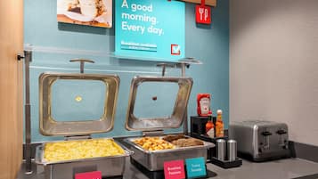 A breakfast buffet with labeled containers for scrambled eggs, potatoes, turkey sausage, and other items.