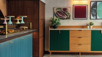 A kitchen with a wooden cabinet, teal and green cabinets, a marble countertop, and a potted plant.