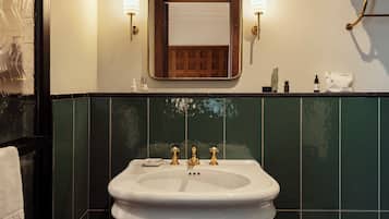A bathroom with a white sink, green tiles, and two wall-mounted lights.