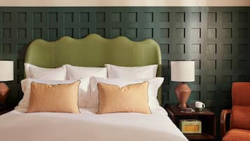 Une chambre d’hôtel avec un lit, deux tables de chevet, une lampe, une chaise et une radio.