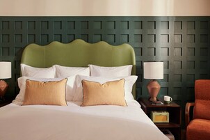 A hotel room with a bed, two bedside tables, a lamp, a chair, and a radio.