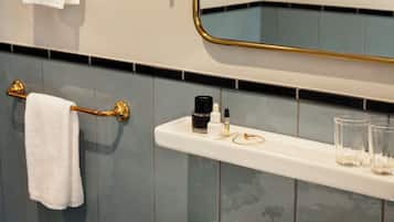 A bathroom with a white sink, gold fixtures, and a mirror with a gold frame.