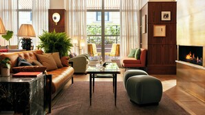 A modern living room with a leather sofa, a glass coffee table, and a fireplace.