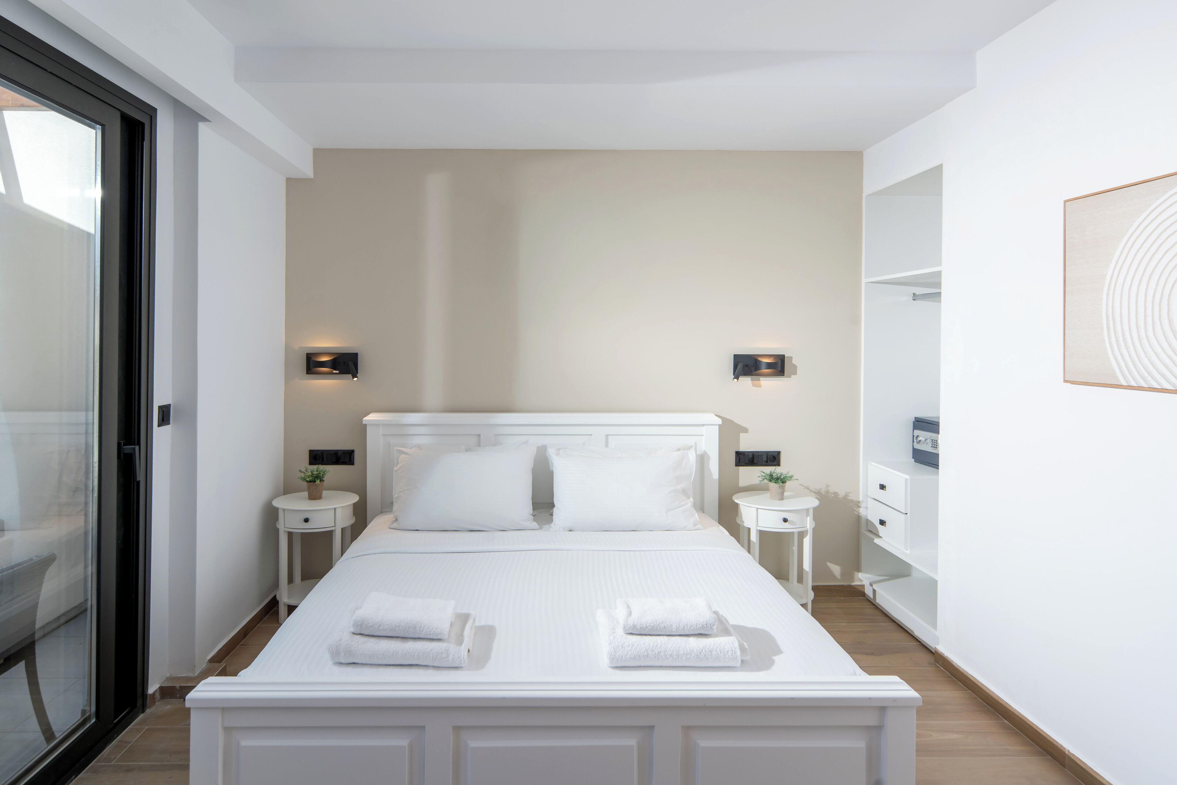 A modern hotel room with a large bed, two bedside tables, a small side table, and a large mirror on the wall.