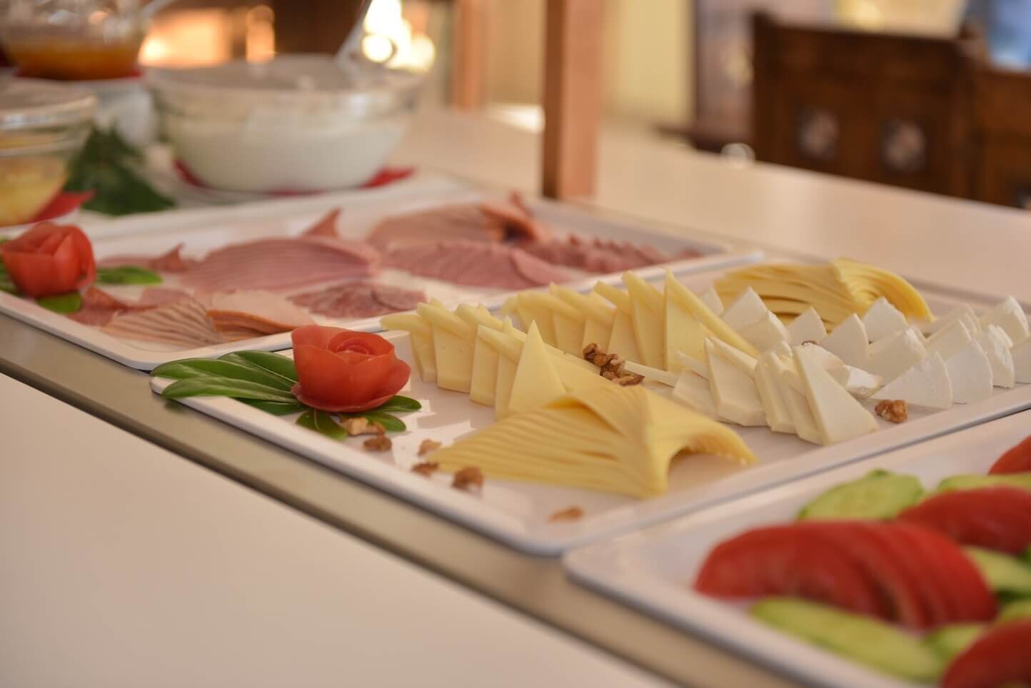 A buffet with various cheeses, fruits, and a decorative rose.