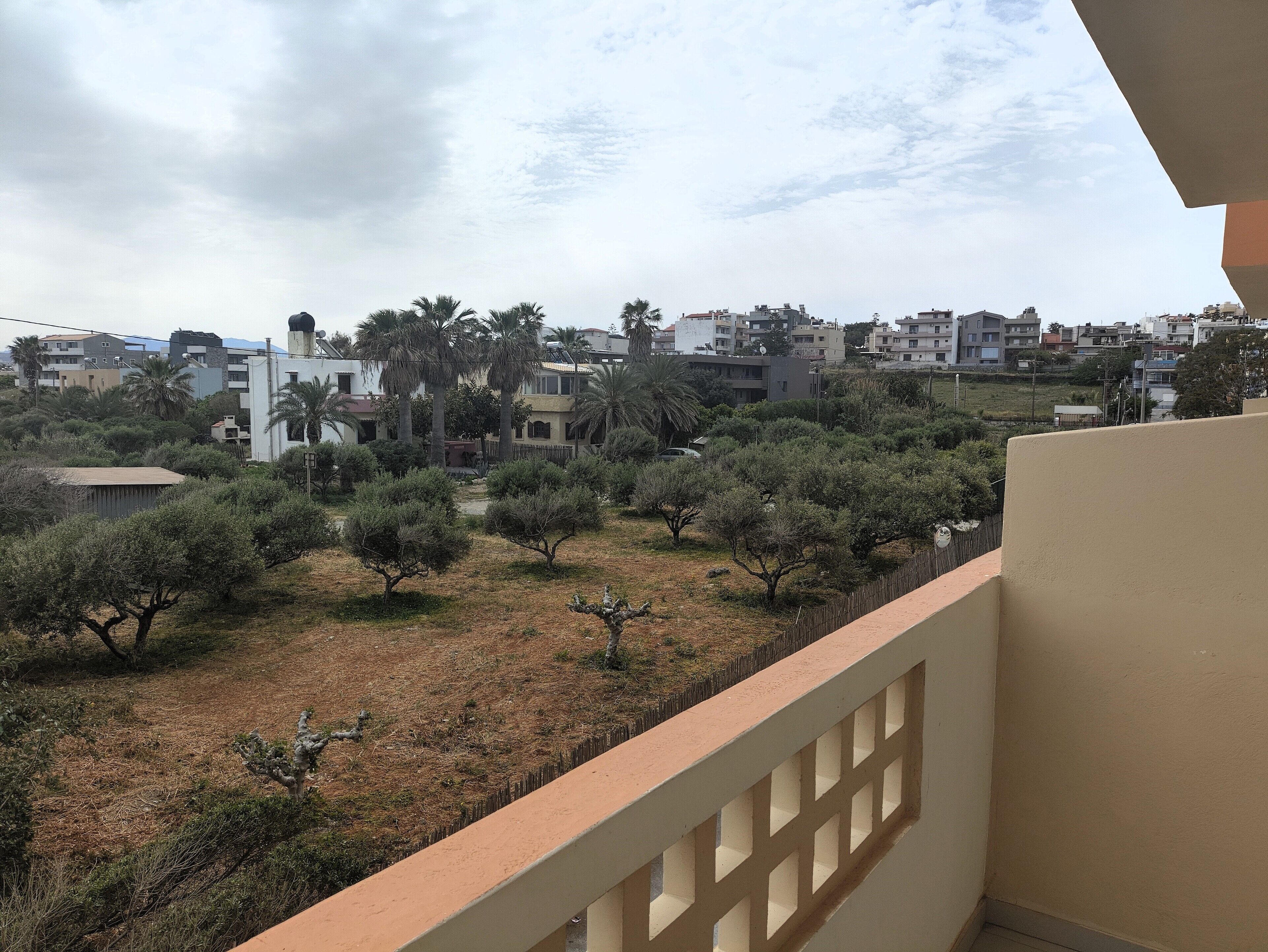 Un balcón con vista a una zona residencial, con casas y árboles.