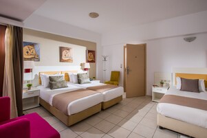 Habitación de hotel con dos camas, un escritorio, una silla y obras de arte en las paredes.
