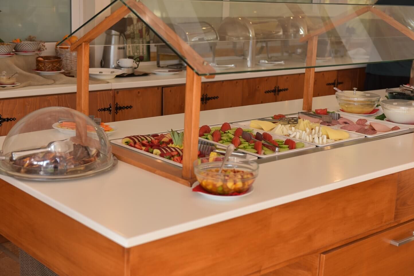 A buffet with various food items, including fruits, cheeses, and meats, displayed in clear containers.