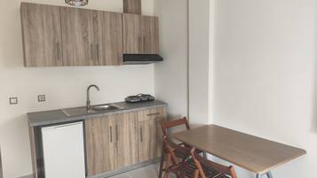 Cocina compacta con armarios de madera, lavavajillas integrado, un lavabo y comedor con mesa y sillas.