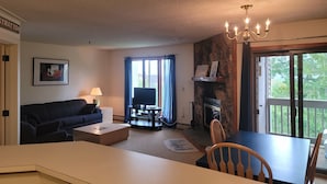 A living room with a sofa, coffee table, TV, fireplace, dining table, and chairs.