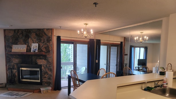 A modern kitchen with a central island, a stone fireplace, and a dining area with chairs.
