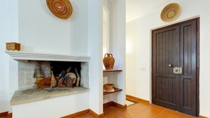 A room with a fireplace, a dark wooden door, and a tiled floor. - Charming "Villa Viola" close to the Beach with Sea View, Terrace & Garden (Narbolia)