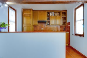 Een keuken met houten kastjes, een betegelde spatwand en een raam.