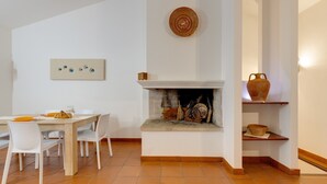 A dining area with a fireplace, white walls, and a tiled floor. - Charming "Villa Viola" close to the Beach with Sea View, Terrace & Garden (Narbolia)