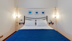A single bed with a blue bedspread, white pillows, and two bedside tables with wall-mounted lamps. - Charming "Villa Viola" close to the Beach with Sea View, Terrace & Garden (Narbolia)